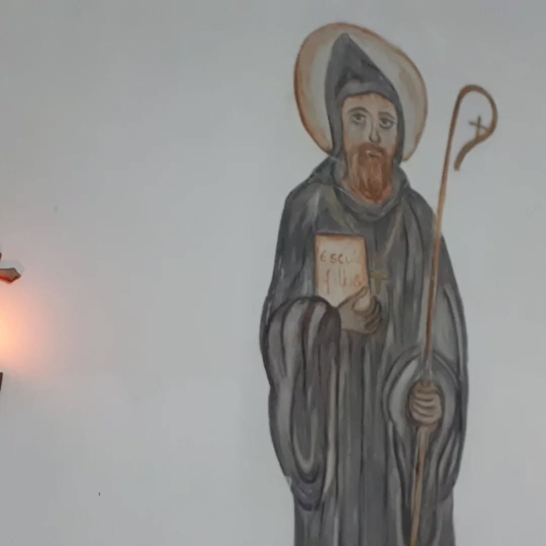 São Bento pintado na parede da igreja, com o báculo e a Regra nas mãos.