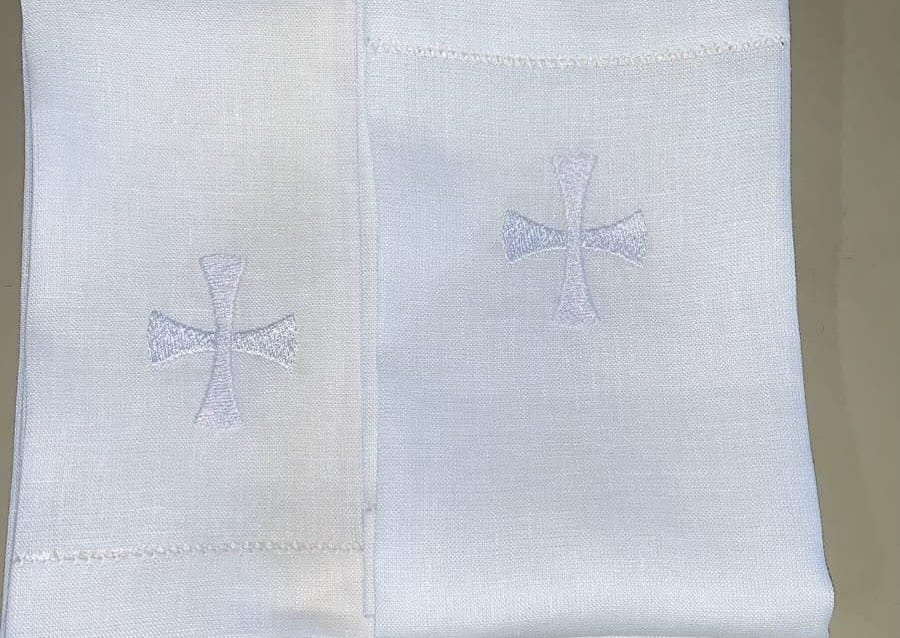 Dois panos de linho com a cruz bordada em branco sobre branco e a barra em ponto ajour.