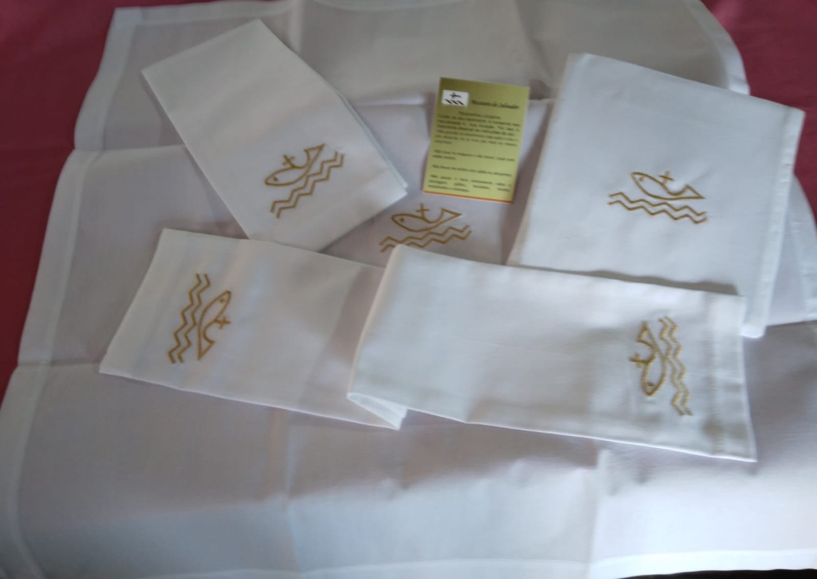 Sanguinhos de linho branco bordados em fio dourado com peixes e o barco.