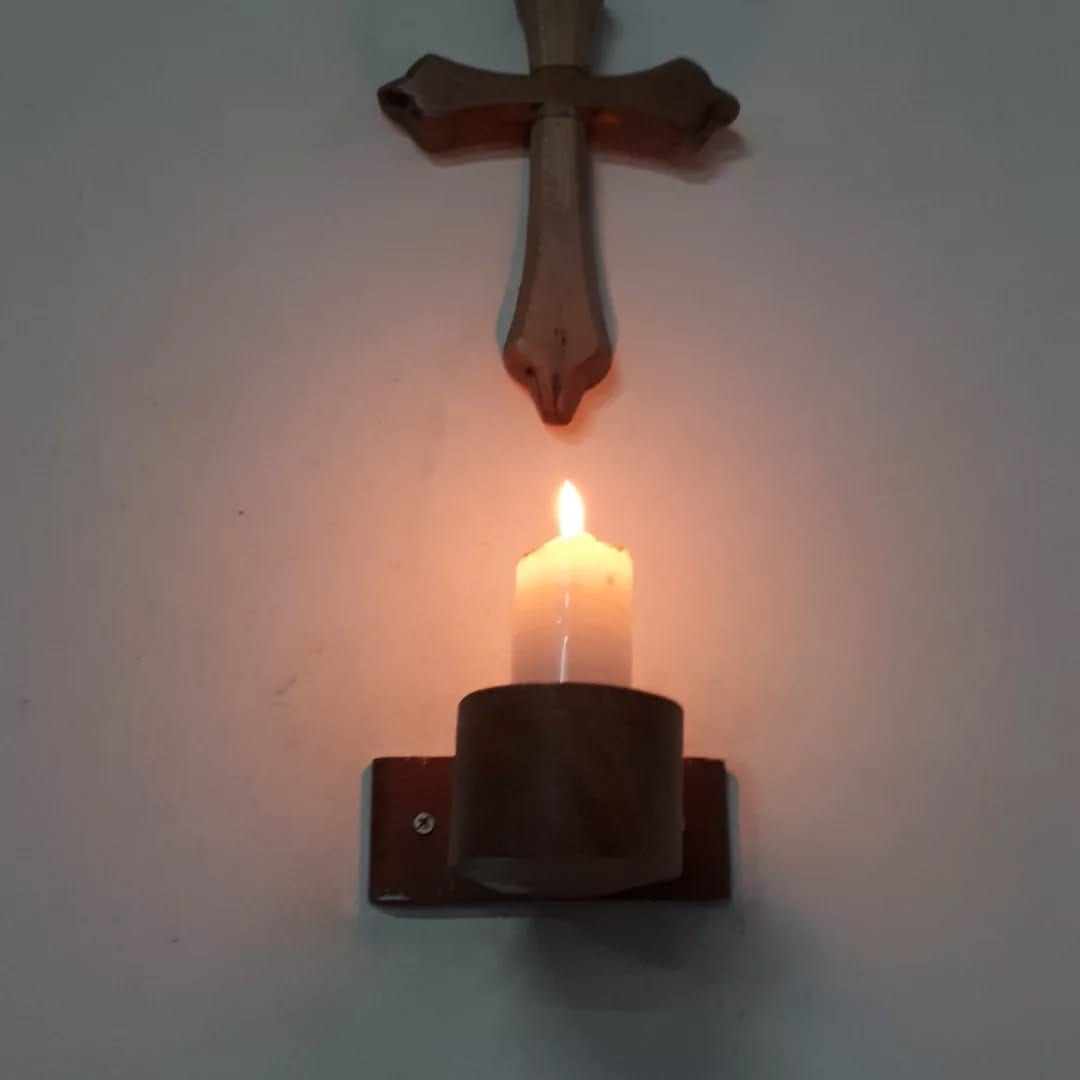 Vela acesa sob o crucifixo da parede.